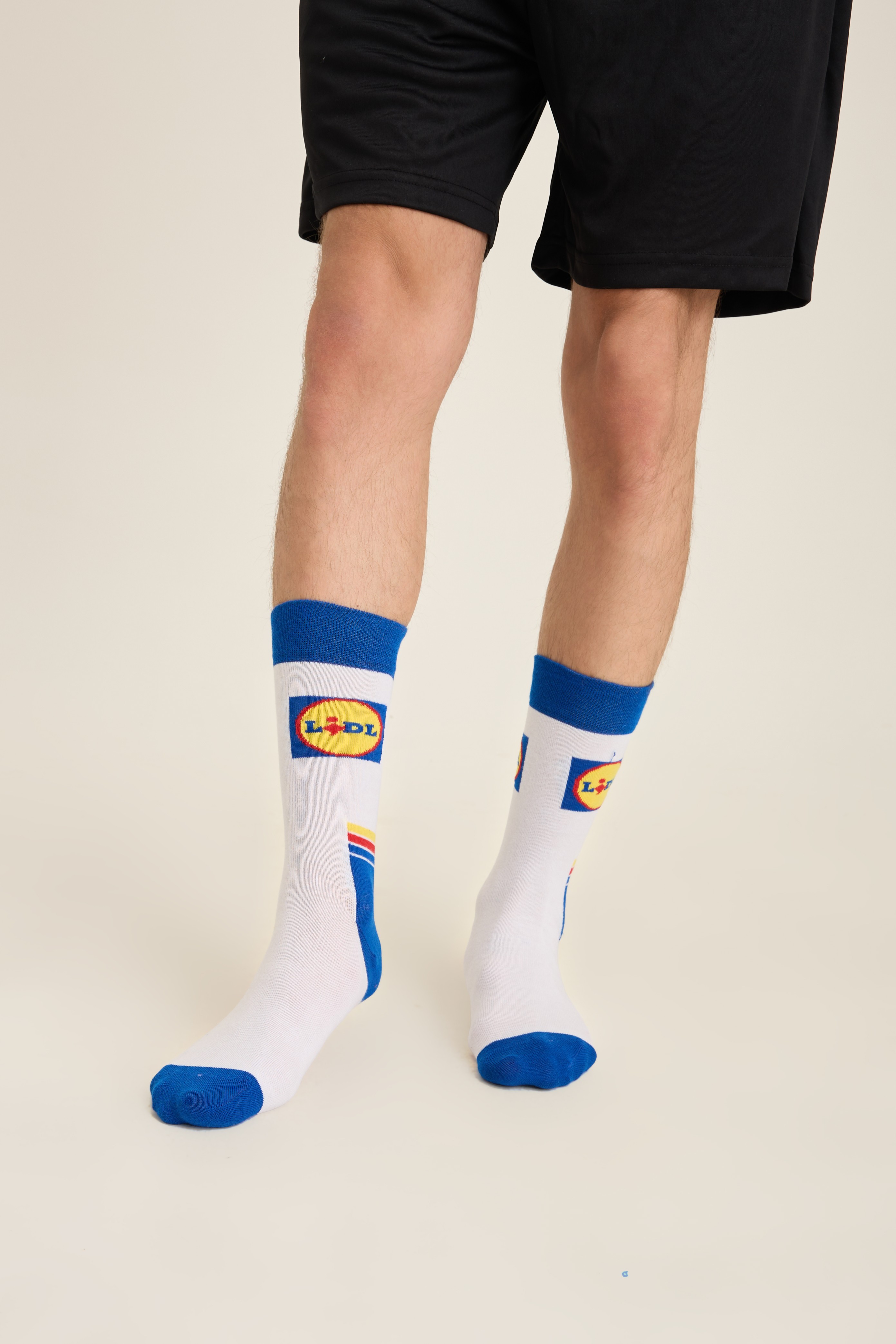White retail-branded socks with blue cuff, yellow logo block and stripe