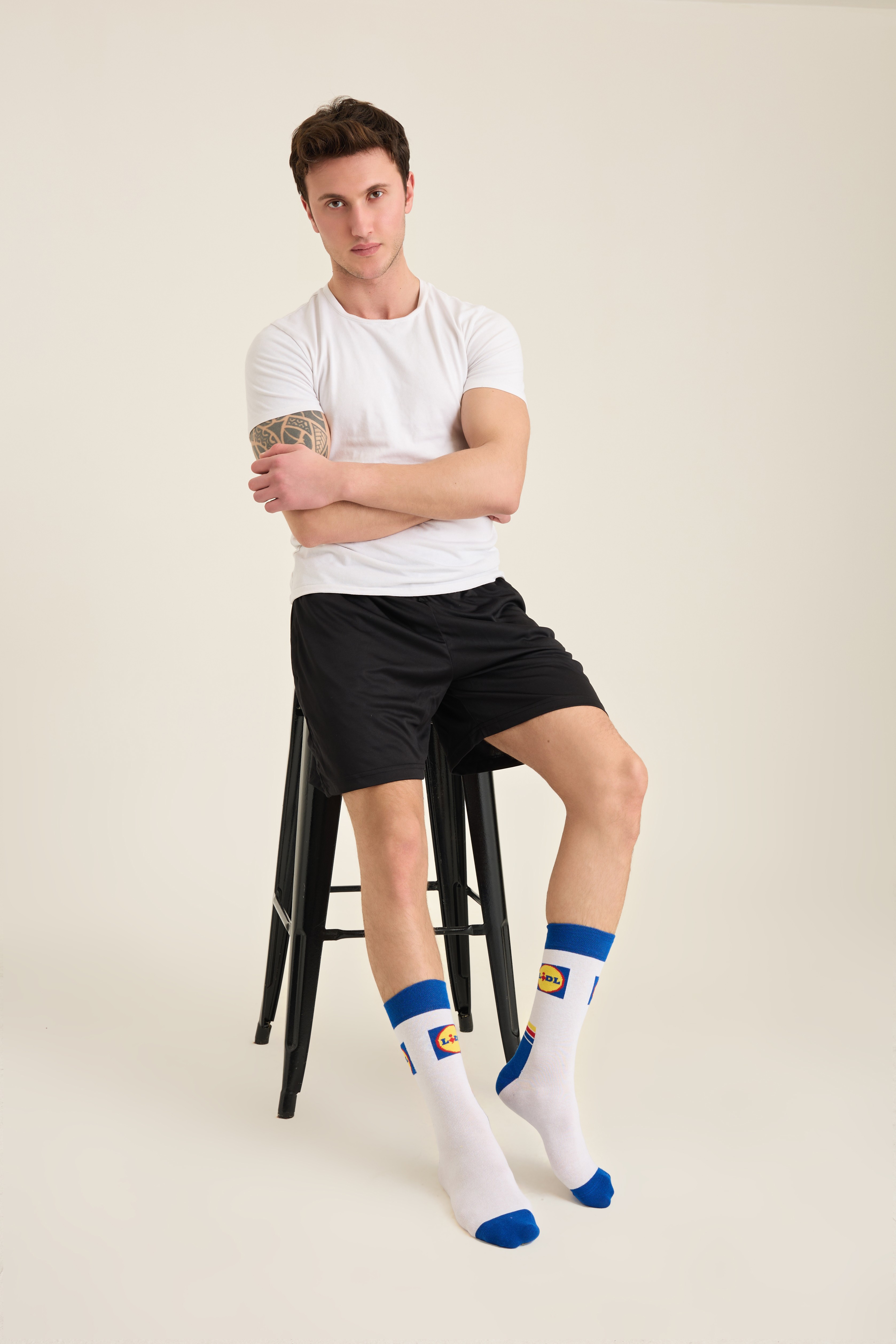 Male model wearing white retail-branded crew socks with blue and yellow detailing